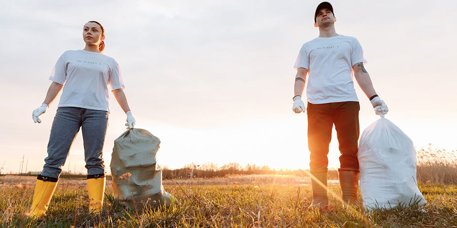 a woman and a man in white tshirts and jeans holding white sacks in a field during sunset